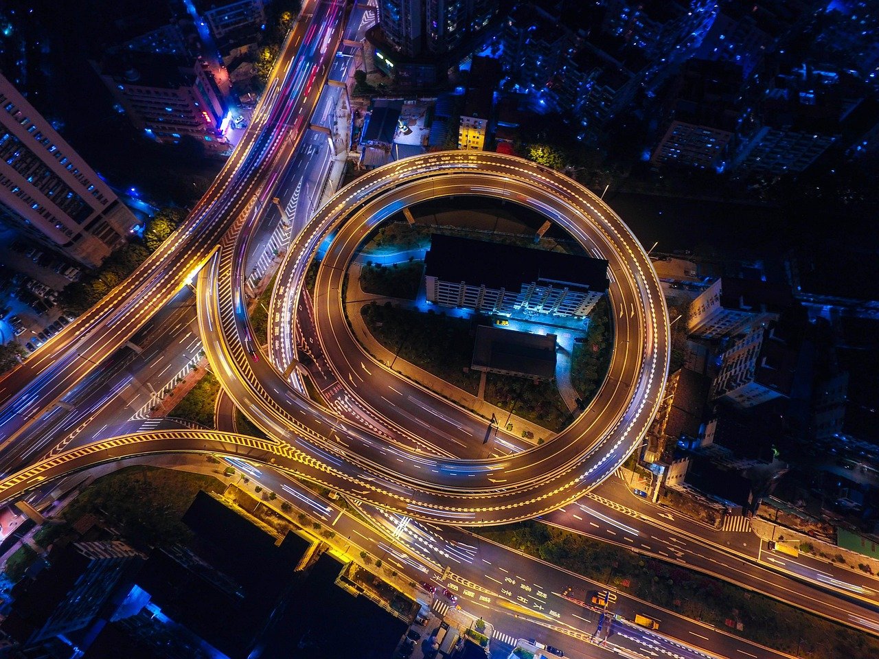 Night aerial view of illuminated highway interchange and city streets