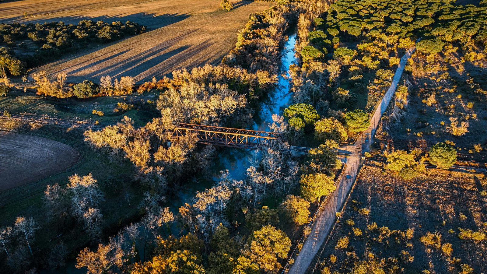 Cinematic aerial view of bridge crossing river and countryside landscape
